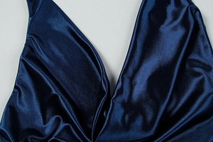 Detailed view of dark blue satin halter neck dress with deep V-neckline and elegant pleats