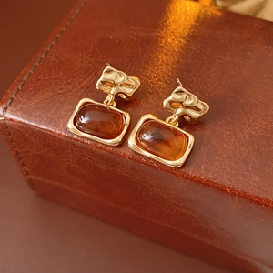 Vue détaillée des boucles d'oreilles vintage en résine ambre sur boîte en cuir