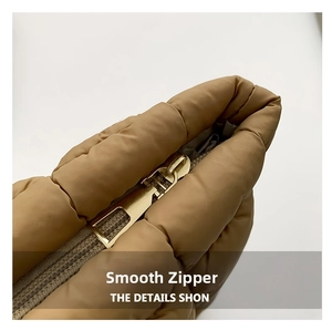 Close-up of smooth gold metal zipper and quilted texture on the khaki puffed makeup bag