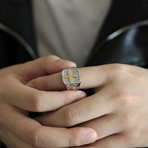 Detail shot of men's hammered silver ring with a central gold cross on hand