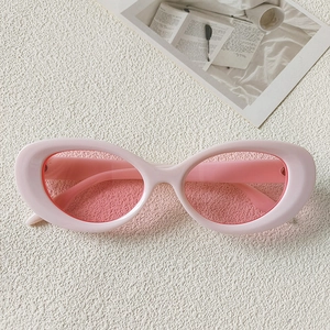 Detailed top view of light pink cat-eye sunglasses on a textured white surface