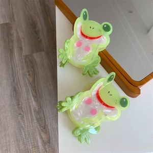 Detail von zwei süßen grünen Frosch-Haarklammern aus marmoriertem Acetat-Material