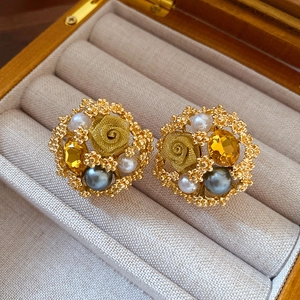 Detail of vintage flower stud earrings with gold rose, pearls, and yellow gemstone