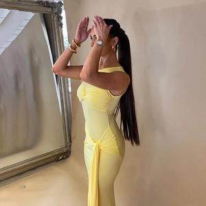 Détail d'une robe jaune moulante avec des cordons de serrage latéraux et un design plissé