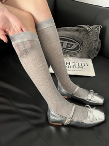 Detail of gray ribbed knee-high socks with small bow accents and silver Mary Jane shoes
