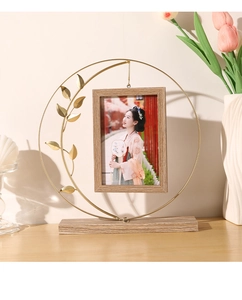 Detail of vintage gold metal round frame with wooden base and a leaf ornament