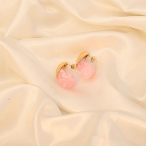 Pink resin teardrop stud earrings with gold metal base on beige silk background