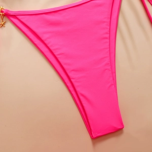 Close-up of pink bikini bottom with shiny texture and golden starfish charm detail