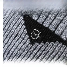 Macro detail of thick knit beanie texture with metal eagle shield emblem on grey fabric