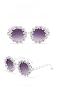 Detailed close-up of white daisy flower sunglasses with gradient grey lenses and clear frames