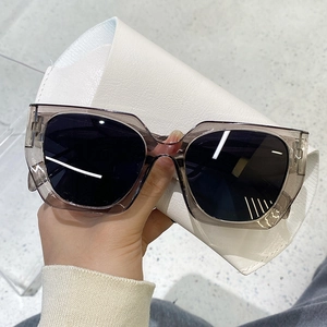 Detail view of large grey transparent sunglasses with dark lenses on leather case
