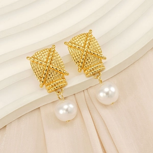 Detail of gold woven square studs with elegant white round pearls on white fabric