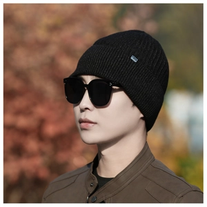 Detail of black winter knit beanie showing fine ribbed texture and metal brand logo