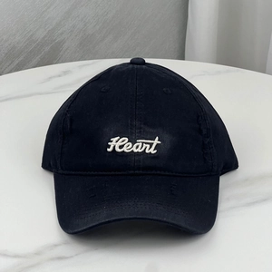 Close-up of distressed black baseball cap featuring white Heart embroidery and torn details