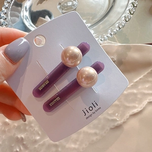 Close-up of purple acrylic hair clips with large pearl and France engraving detail