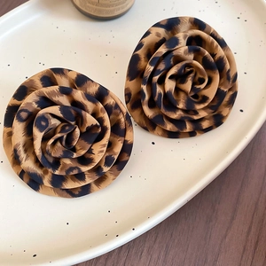 Close-up of fabric flower earrings with leopard print on an elegant oval jewelry tray
