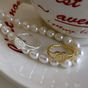 Close-up of gold and silver heart smiley rings with vintage texture on white tray