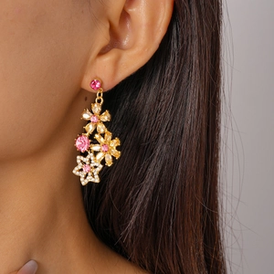 Close-up of pink and clear floral crystal earrings worn on a gold setting