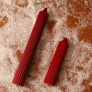 Detailansicht von roten gerippten Stumpfkerzen auf Schneehintergrund für Weihnachtsdeko.