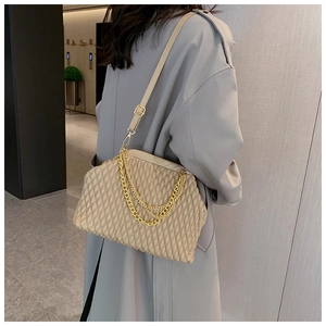 Close-up of beige quilted crossbody bag featuring a gold chain and leather strap details