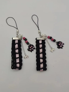 Detail of handmade black lace and pink ribbon phone charm with cat and bead accents