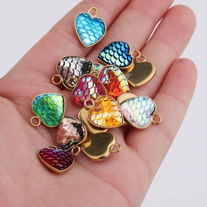 Handheld view of gold-plated heart fishscale pendants in blue, green, and red