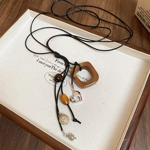 Detailed shot of retro pendant necklace with wooden beads and silver heart charm on black cord