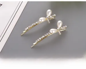 Detail view of two gold butterfly hair clips with teardrop pearls and crystals