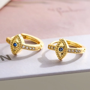 Macro detail of gold-plated evil eye hoop earrings with blue stone and cubic zirconia