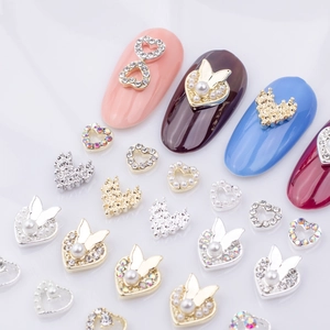 Macro view of alloy heart and butterfly nail charms with rhinestones and pearls on nails