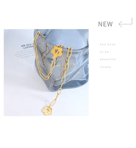 Detail of gold flower toggle clasp and thick chain necklace on elegant glass background
