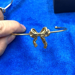 Détail d'un bracelet jonc doré avec nœud tenu sur un fond en velours bleu élégant
