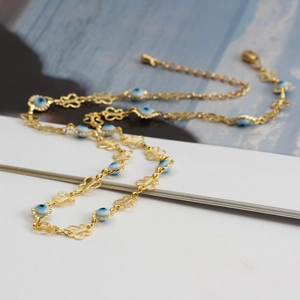 Close-up of golden butterfly link necklace with blue evil eye beads and adjustable clasp