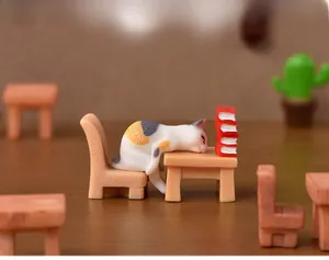 Statuetta in resina di gatto calicò in miniatura seduto a una scrivania con piccoli libri