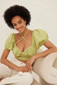Close-up of light green puff sleeve top with off-shoulder cut and textured fabric details