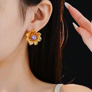 Close-up of vintage flower earrings with purple zircons worn on model with dark background