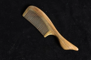Macro shot of natural green sandalwood comb showing unique wood grain on black background