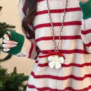 Close-up of handmade crochet snowflake pendant with red velvet bow on a Christmas necklace