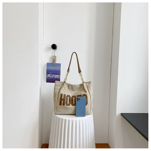 Detailed size comparison of a large beige tote bag next to a smartphone device