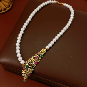 Détail du collier de perles vintage avec pendentif floral doré et pierres colorées