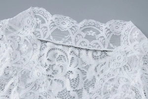 Gros plan sur le motif floral en dentelle blanche et le décolleté en V de la robe