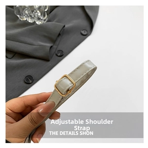 Detail of adjustable light gray leather shoulder strap with gold metal buckle and fine stitching
