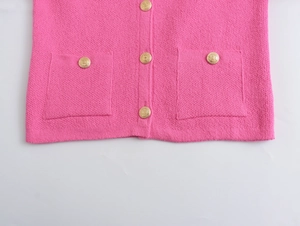 Macro detail of pink knit cardigan featuring gold buttons and woven texture patterns