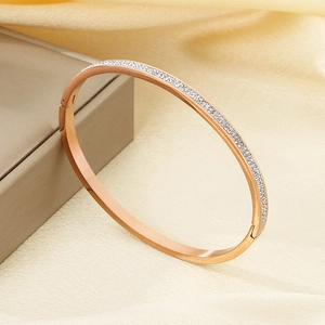 Dettaglio di un bracciale ovale in oro rosa con finitura spazzolata e pavé di zirconi