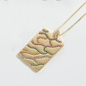 Macro shot of rectangular gold pendant with wavy multi-color cubic zirconia inlay