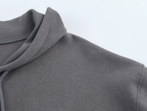 Detailed close-up of dark grey ribbed knit hoodie neckline and stitching craftsmanship