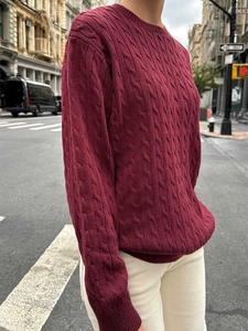 Close-up of wine red crewneck knit sweater featuring classic cable-knit texture detail