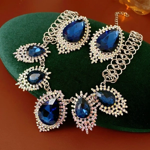 Detail of luxury teardrop necklace and earrings set with blue stones on velvet padding