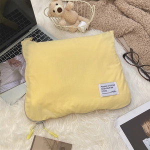 Detail of light yellow quilted laptop sleeve with silver zipper and white label