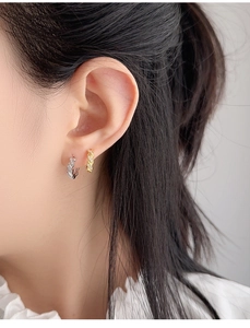 Macro close-up of gold and silver twisted rope hoop earrings with micro-inlaid diamonds